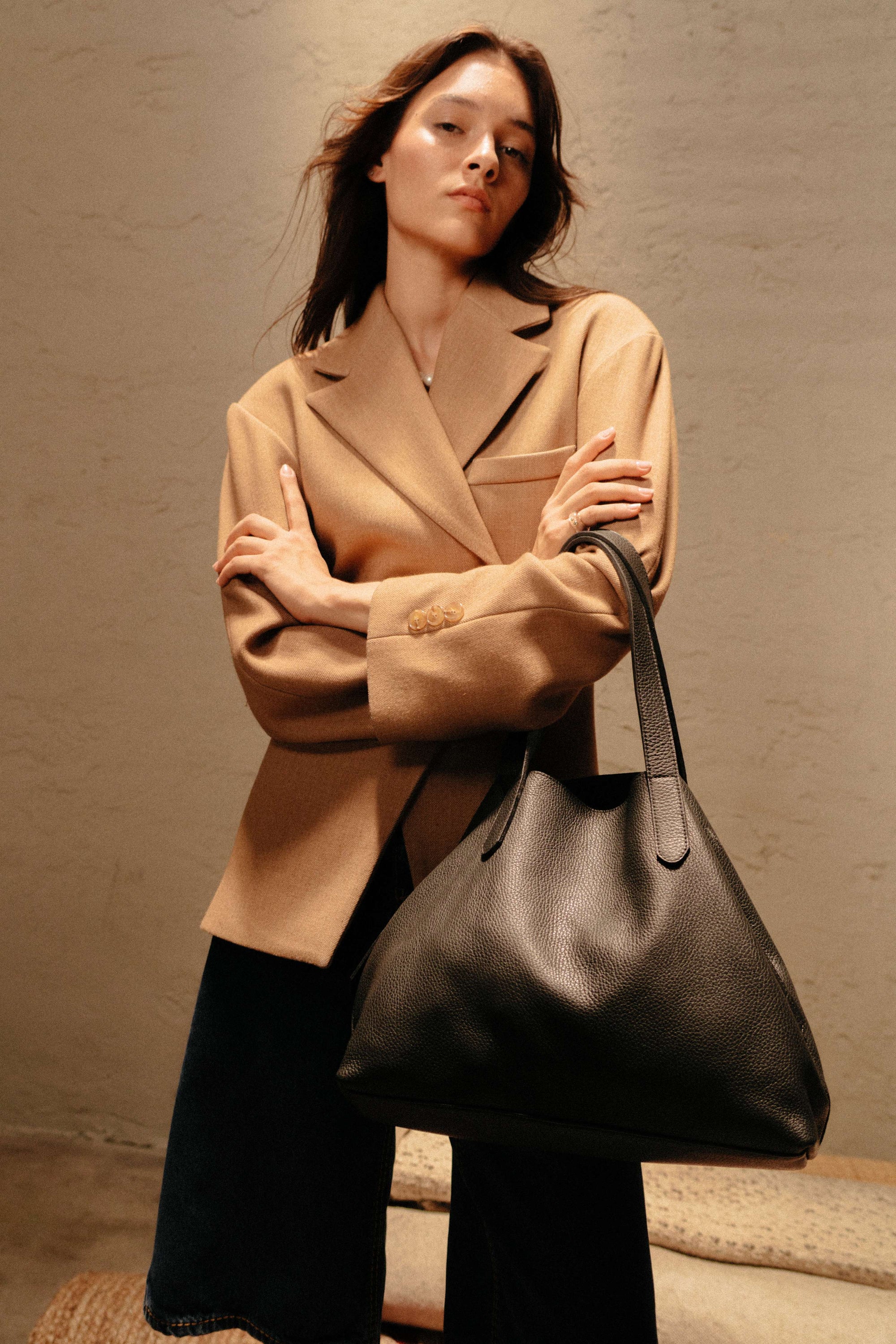 Woman holding a black handbag against a neutral background
